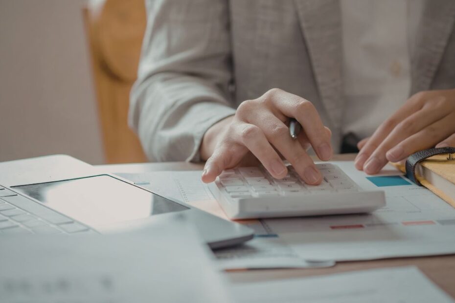 Pessoa usando calculadora e laptop. Como fazer um controle de gastos pessoais eficiente?
