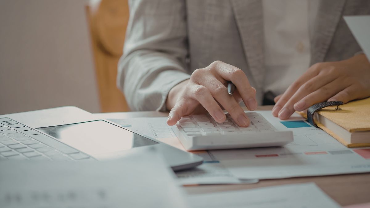 Pessoa usando calculadora e laptop. Como fazer um controle de gastos pessoais eficiente?