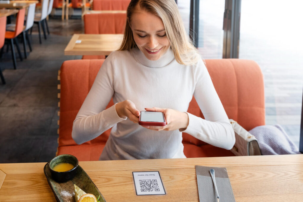 Mulher usando celular para pagamento por Pix Automático em um pequeno negócio
