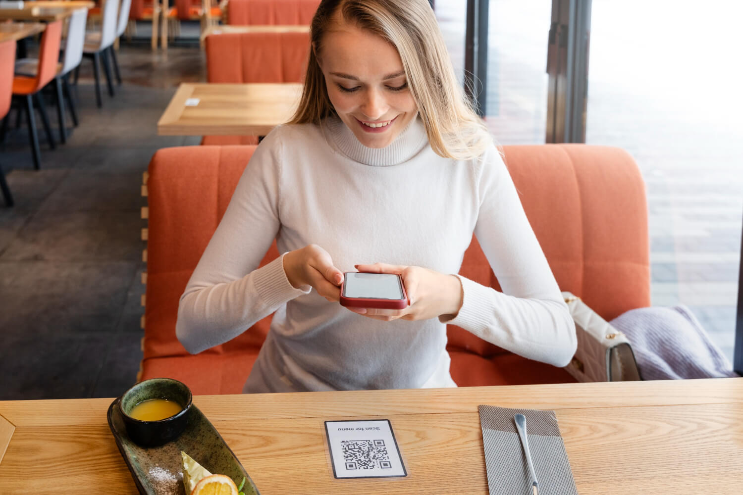 Mulher usando celular para pagamento por Pix Automático em um pequeno negócio